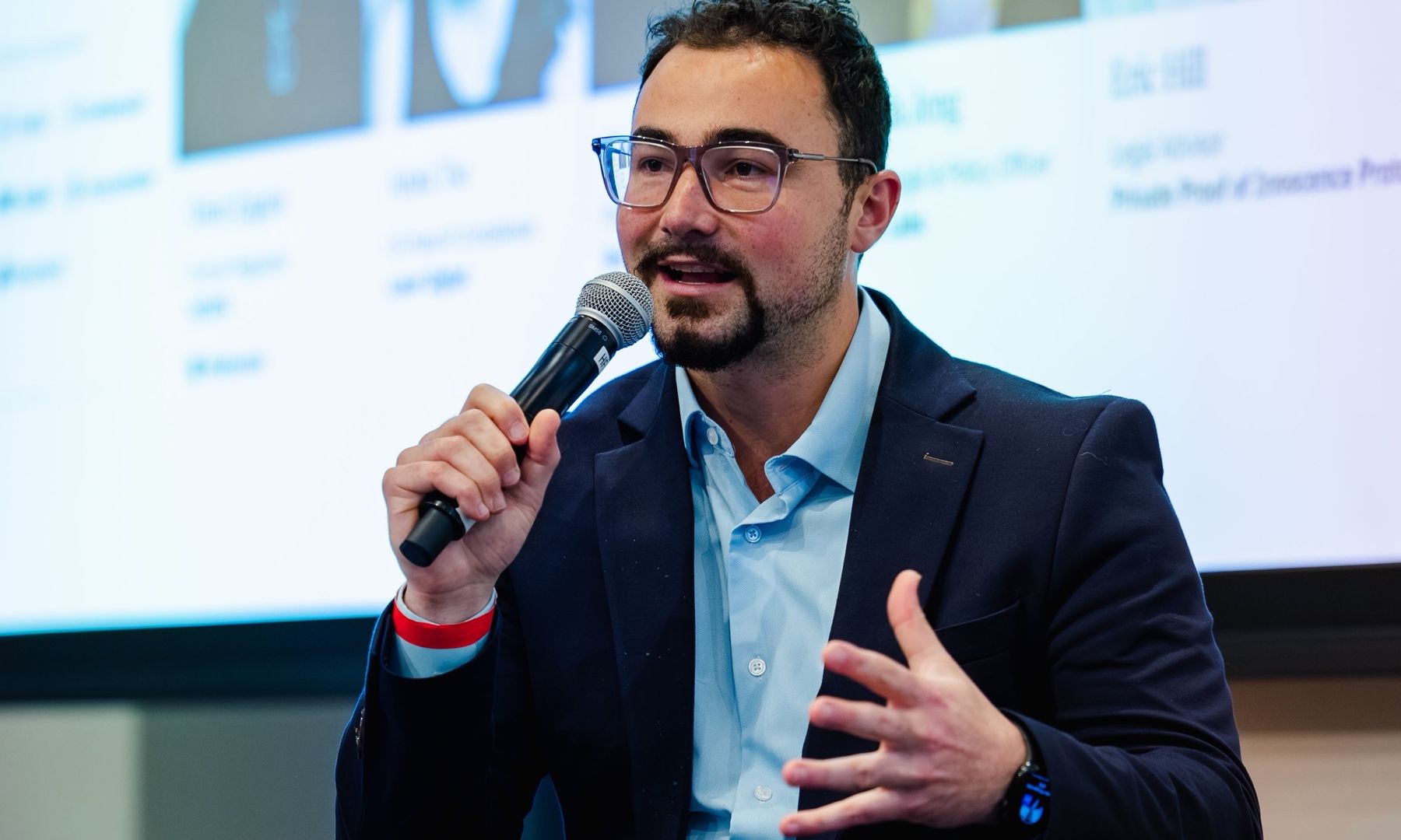 Dominic speaking on a panel, holding a microphone