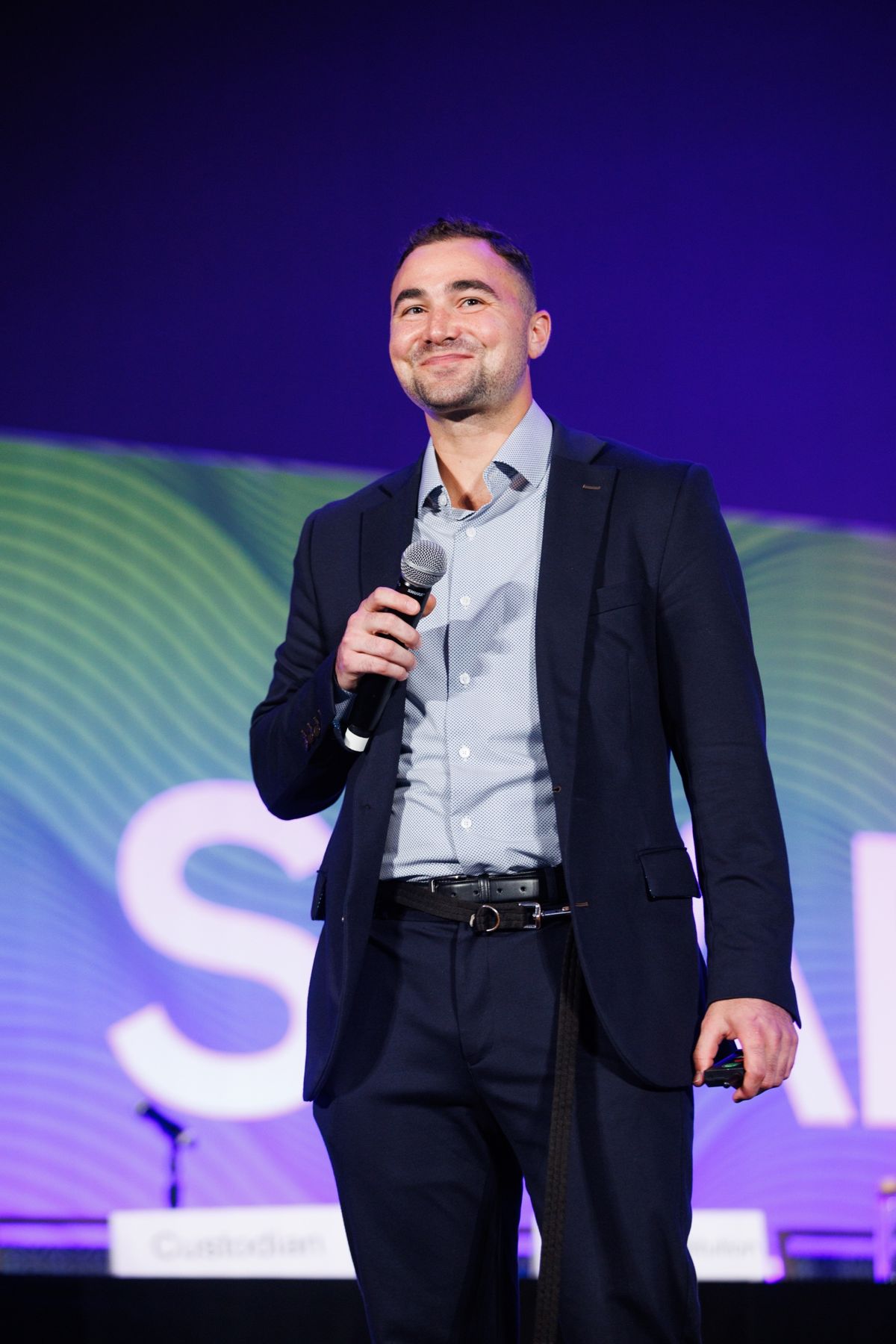 Portrait of Dominic Zagara on stage holding a microphone